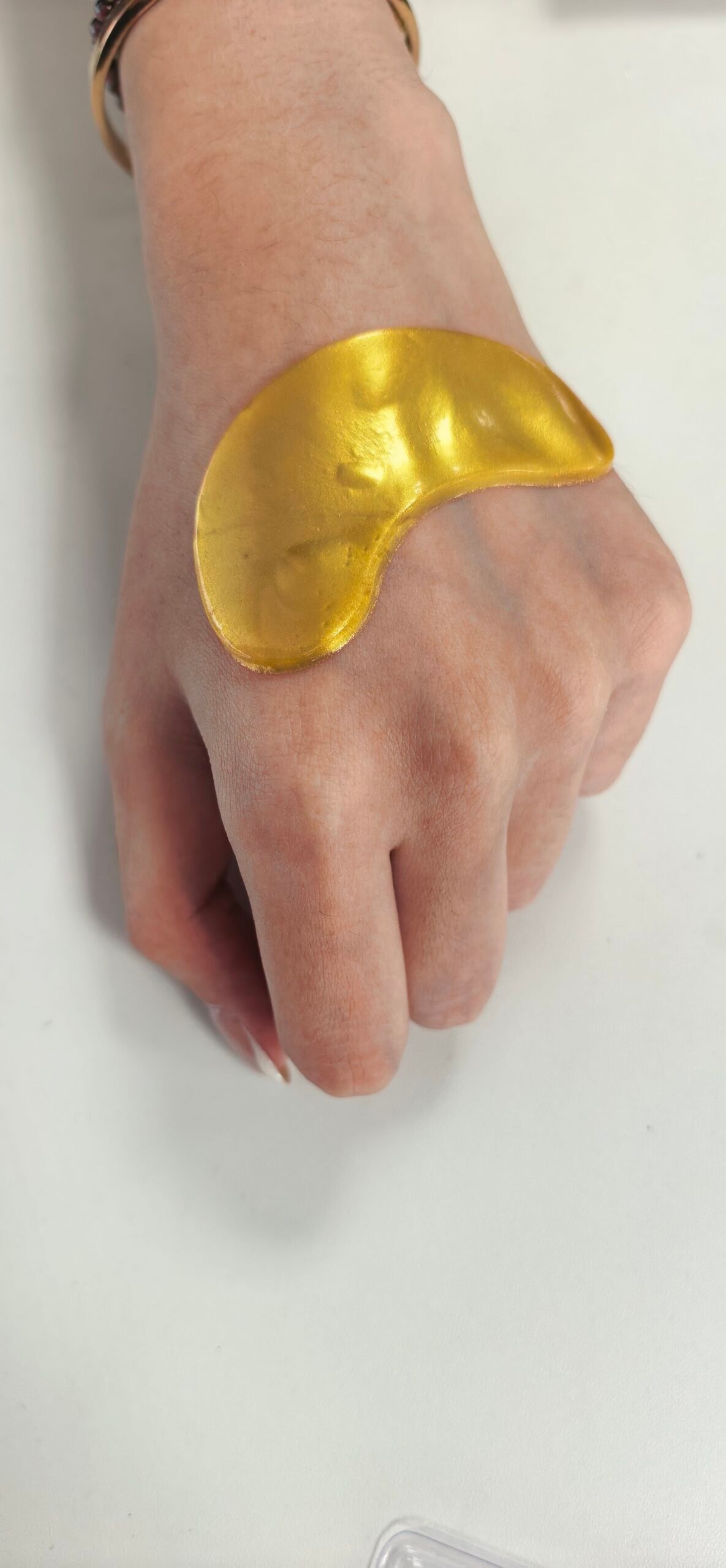 Maskiss gold hydrogel eye patch shown on skin to demonstrate size and texture